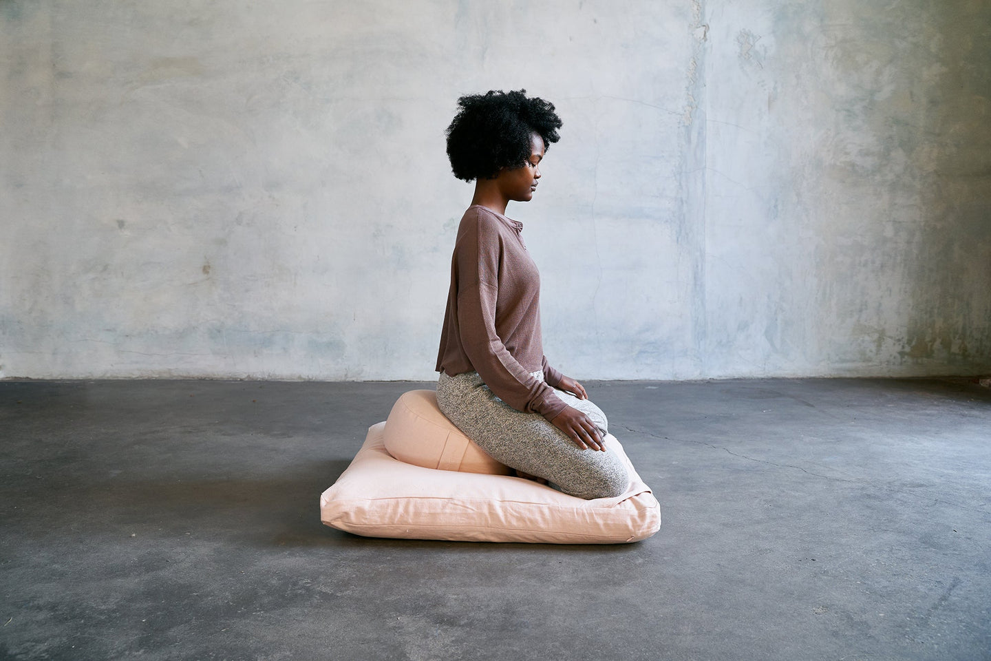 Meditation practitioner sitting on renoo meditation pillows in dawn color set of zafu and zabuton.